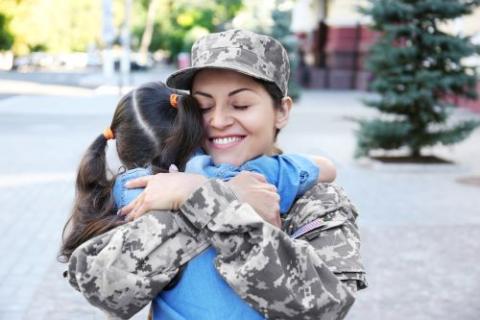 Female service member hugging a small child